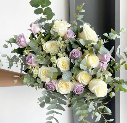 A lovely bouquet with lavender-pink and white roses, lavender clematis, and eucalyptus cinerea.