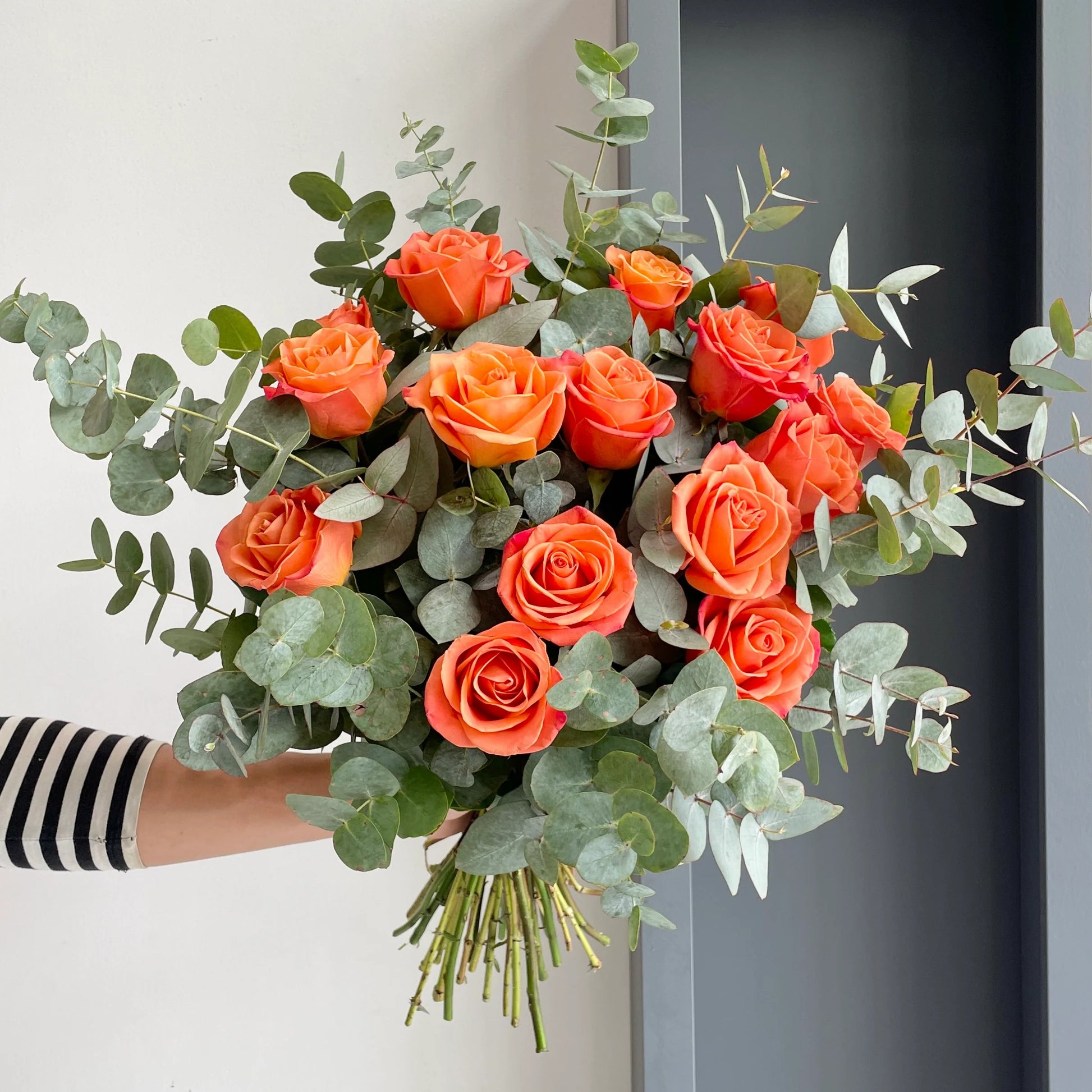 A beautifully arranged bouquet that comprises our Orange Juice roses paired with fragrant eucalyptus cinerea!